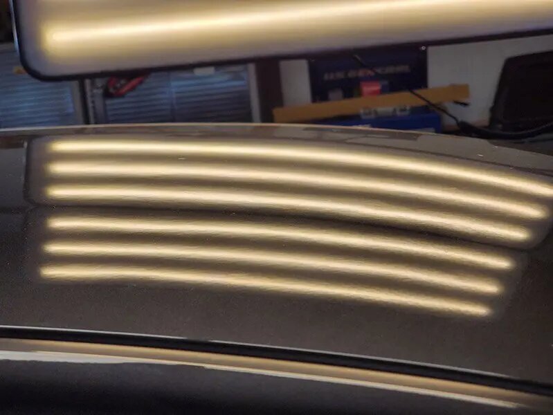Same roof panel dent-free under PDR inspection light after repair