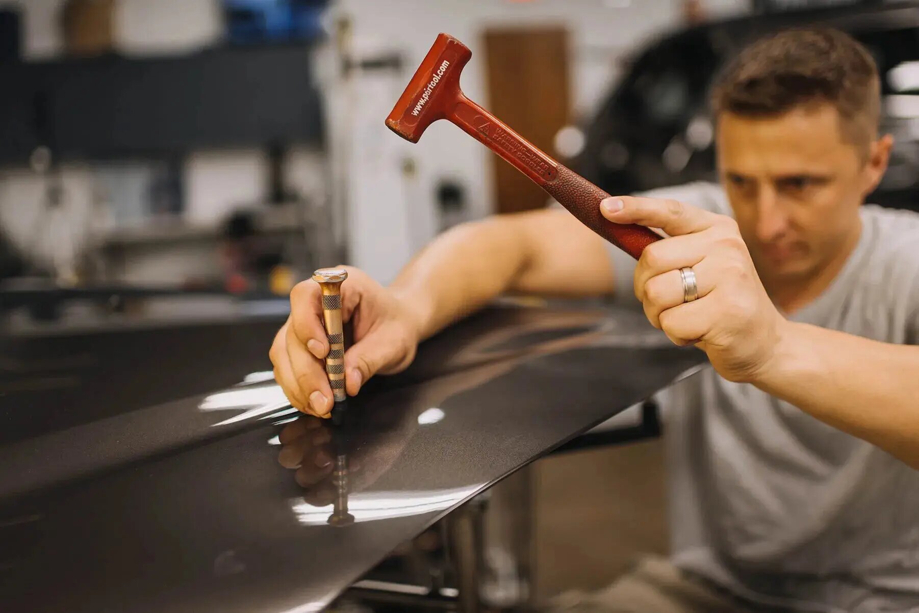 A DentPicks technician working a white Porsche 911 under PDR lighting